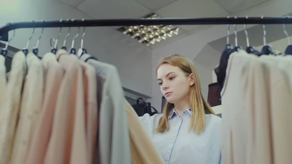 Een leuk meisje kiest kleren in een winkel. Winkelen — Stockfoto