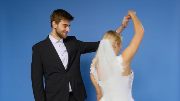De bruid en bruidegom in trouwpakken dansen op een blauwe achtergrond. Bruiloft — Stockvideo