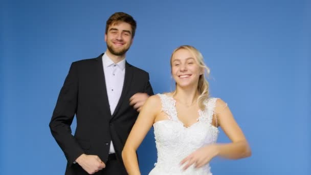 Жених и невеста в свадебных костюмах танцуют на синем фоне. Свадьба — стоковое видео