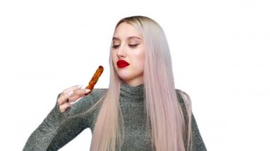 Dudaklarını kırmızı rujla boyayan, makyajını kirletmemek için dikkatlice yiyen bir kızın yakın çekimi. Beyaz bir arka planda. Diyet olsun. Sağlıklı ve sağlıksız gıda kavramı. fast food