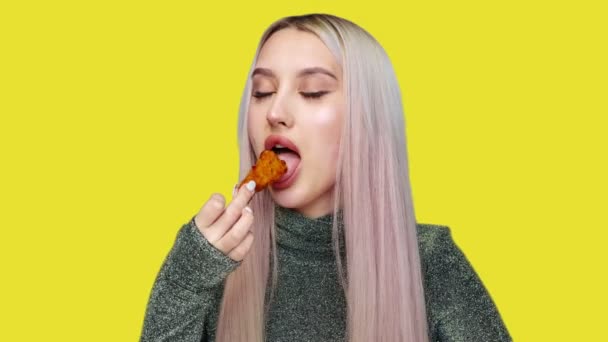 Κοντινό πλάνο ενός όμορφου κοριτσιού που τρώει πρόχειρο φαγητό σε κίτρινο φόντο. Δίαιτα. Η έννοια των υγιεινών και ανθυγιεινών τροφίμων. fast food — Αρχείο Βίντεο