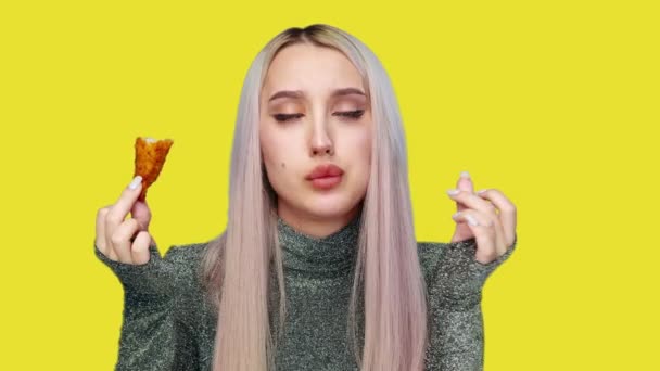 Close-up de uma menina bonita sexualmente comer fast food em um fundo amarelo. Dieta. O conceito de comida saudável e insalubre. fast food — Vídeo de Stock