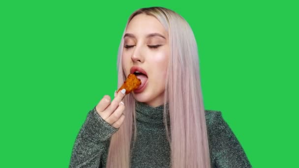 Κοντινό πλάνο ενός όμορφου κοριτσιού που τρώει πρόχειρο φαγητό σε πράσινο φόντο. Δίαιτα. Η έννοια των υγιεινών και ανθυγιεινών τροφίμων. fast food — Αρχείο Βίντεο
