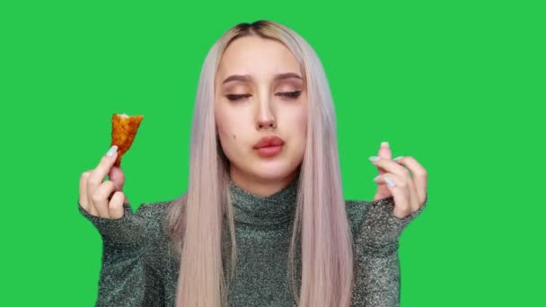 一个漂亮女孩的特写镜头，在绿色背景下吃快餐。节食。健康和不健康食品的概念。快餐食品 — 图库视频影像