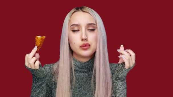 Primo piano di una bella ragazza che mangia sessualmente fast food su uno sfondo rosso. Dieta. Il concetto di cibo sano e malsano. fast food — Video Stock