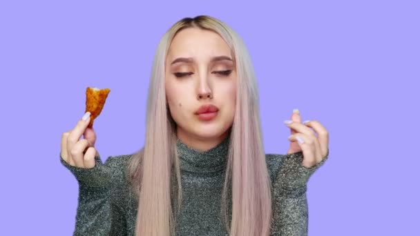 Primo piano di una bella ragazza che mangia sessualmente fast food su uno sfondo viola. Dieta. Il concetto di cibo sano e malsano. fast food — Video Stock