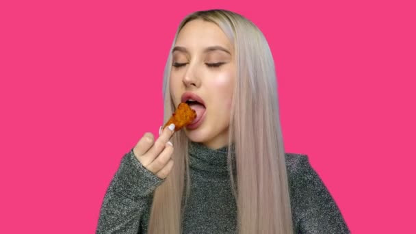 Primo piano di una bella ragazza che mangia sessualmente fast food su uno sfondo rosa. Dieta. Il concetto di cibo sano e malsano. fast food — Video Stock