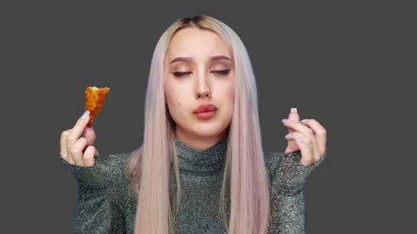 一个漂亮女孩在灰色背景下吃快餐的特写镜头。节食。健康和不健康食品的概念。快餐食品 — 图库视频影像