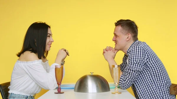 Ένας άντρας και ένα κορίτσι σε ραντεβού τρώνε φαστφουντάδικα και πίνουν ποτά από ποτήρια σε κίτρινο φόντο. Ραντεβού. Η έννοια των υγιεινών και ανθυγιεινών τροφίμων. Γρήγορο φαγητό — Φωτογραφία Αρχείου