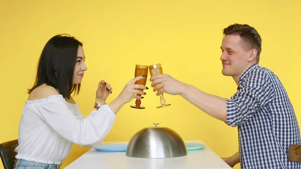 Ένας άντρας και ένα κορίτσι σε ραντεβού τρώνε φαστφουντάδικα και πίνουν ποτά από ποτήρια σε κίτρινο φόντο. Ραντεβού. Η έννοια των υγιεινών και ανθυγιεινών τροφίμων. Γρήγορο φαγητό — Φωτογραφία Αρχείου