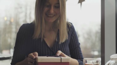 Bir adam masanın altından bir hediye kutusu alır ve bir kafe veya restoranın yakın planında masanın üzerine koyar.