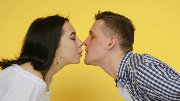 Close-up de uma mulher e um homem que está comendo batatas fritas e beijando ternamente em um fundo amarelo. O conceito de comida saudável e insalubre. Fast food — Fotografia de Stock