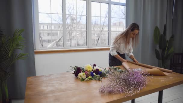 A young beautiful woman engaged in floristry begins to collect the best flowers for her flower arrangement. Floristry — Stock Video