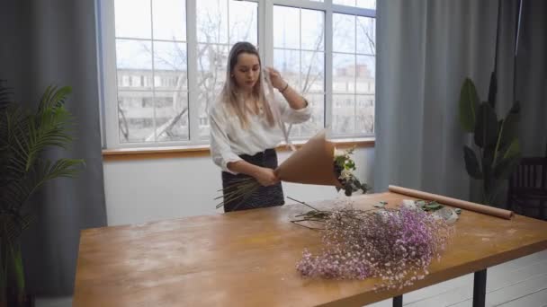 Seorang wanita muda cantik yang terlibat dalam karangan bunga mulai mengumpulkan bunga terbaik untuk pengaturan bunganya. Floristry — Stok Video