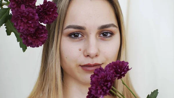 Närbild av en tjejs ansikte med ren slät hud, med vackra dahlior bredvid ansiktet. Förlaga — Stockfoto