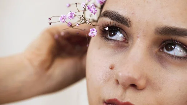 Chicas cara con la piel limpia y suave, maquillaje desnudo en el fondo de las ramas de gypsophila en el estudio. Modelo —  Fotos de Stock