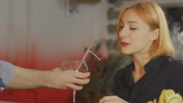 Holka sedí v baru se sklenkou vína v ruce a komunikuje s barmanem. — Stock video