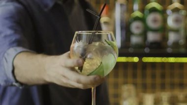 Barmen bir bardak getirdi, alkollü bir kokteyl, ve tezgahın üzerine koydu. Yakın plan.