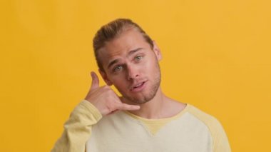Ara beni. Sarı Arkaplan Üzerinde Telefon Hareketi Gösteren Yakışıklı Genç Adam