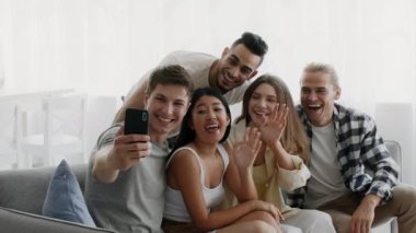 Ev partisinde akıllı telefonla video görüşmesi yapan çok kültürlü arkadaşlar grubu.