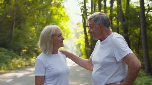 Pozitif emeklilik kavramı. Neşeli kıdemli adam ve bayan birbirleriyle konuşuyorlar, parkta duruyorlar ve gülüyorlar. — Stok video