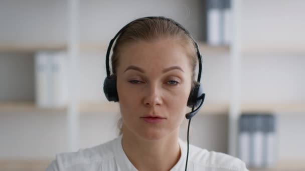 Operator gorącej linii. Portret młodej kobiety w słuchawkach rozmawia przed kamerą — Wideo stockowe