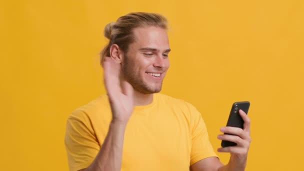 Jovem alegre com Smartphone fazendo chamada de vídeo, acenando a mão na câmera — Vídeo de Stock