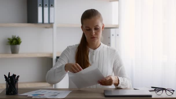 Seriöse junge Geschäftsfrau öffnet Umschlag und liest Brief am Arbeitsplatz im Büro — Stockvideo