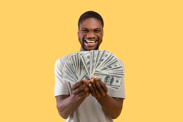 Huge profit concept. Wealthy black man with lots of money excited over his big success over yellow background — Stock Photo, Image