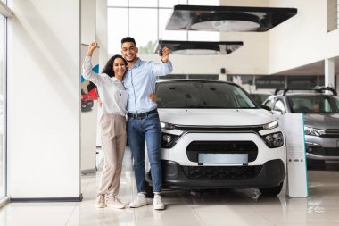 Neşeli orta doğu çifti yeni otomobillerinin anahtarını gösteriyor.