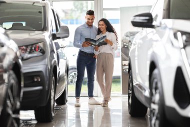 Lüks araba salonunu ziyaret eden neşeli Arap çift.