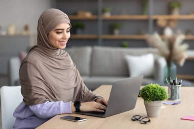 Masada oturan gülümseyen Müslüman kadın.