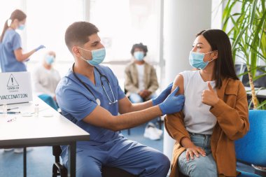 Aşılanmış Asyalı Kadın Klinikte Baş Parmakla İşaret Ediyor