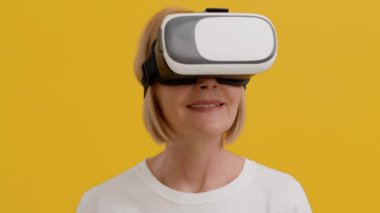 VR kulaklık takan mutlu yaşlı kadın heyecandan başını çeviriyor.