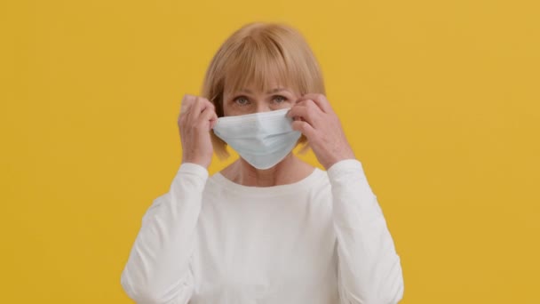 Glad Senior Woman tar av skyddande ansiktsmask och ler mot kameran — Stockvideo