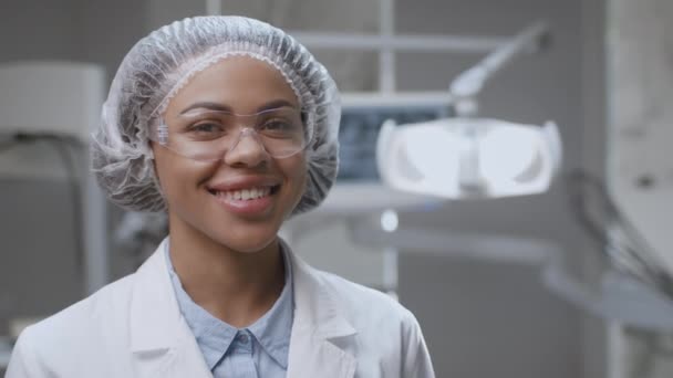 Professionelle Zahnmedizin. Positive afrikanisch-amerikanische Zahnärztin lächelt in die Kamera, posiert in Zahnklinik, freier Raum — Stockvideo
