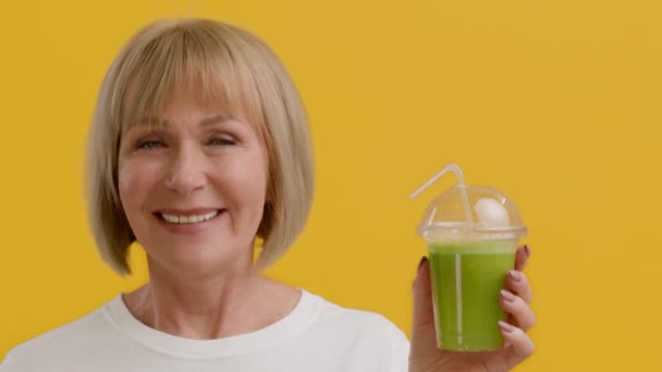 Dieta odwykowa. Uśmiechnięta seniorka trzymająca szkło ze Smoothie i Kiwającą Głową — Wideo stockowe