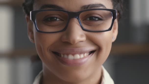 Primer plano retrato de joven afro-americana positiva dama en gafas sonriendo a cámara, cámara lenta — Vídeos de Stock