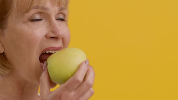 Dents fortes et saines. Happy Senior Femme mordant pomme fraîche et souriant — Video