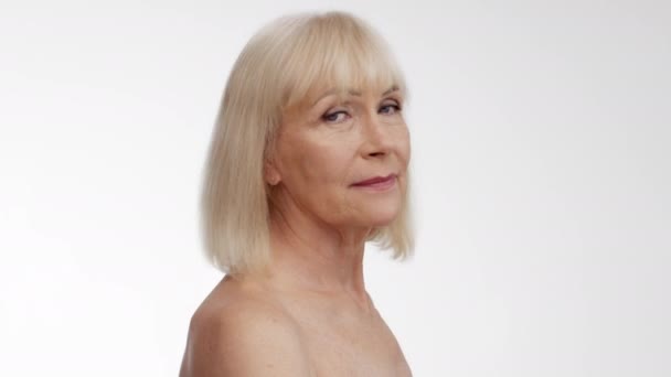 Beleza do envelhecimento. Perfil retrato de linda senhora sênior com ombros nus virando rosto para câmera e sorrindo — Vídeo de Stock