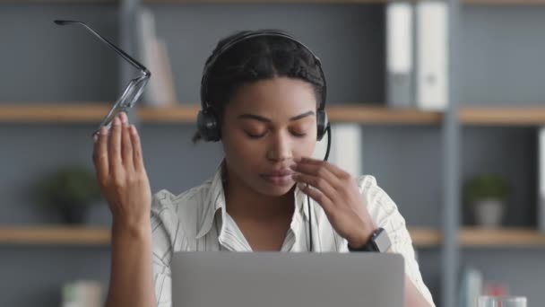 Concepto de exceso de trabajo. Cansado afroamericano dama llamada centro operador que sufre de dolor de cabeza, frotando puente de la nariz — Vídeos de Stock