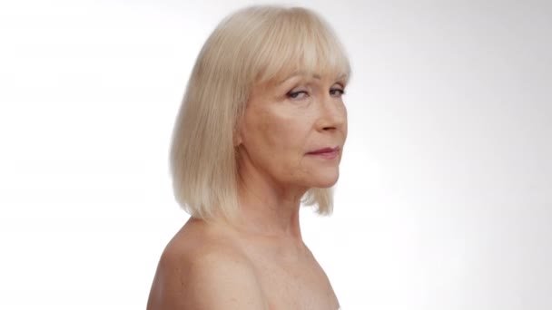 Beauty portrait of mature well-groomed woman turning face to camera and smiling, posing with bare shoulders — Stock Video