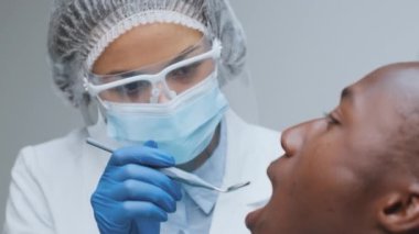 Genç Afrikalı Amerikalı hasta diş sağlığı kliniğinde önleyici sağlık kontrolü sırasında ağzını açıyor.