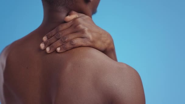 Muskelschmerzen. Unerkennbarer muskulöser afrikanisch-amerikanischer Mann leidet unter Schulterschmerzen, massiert und wärmt den Nacken — Stockvideo