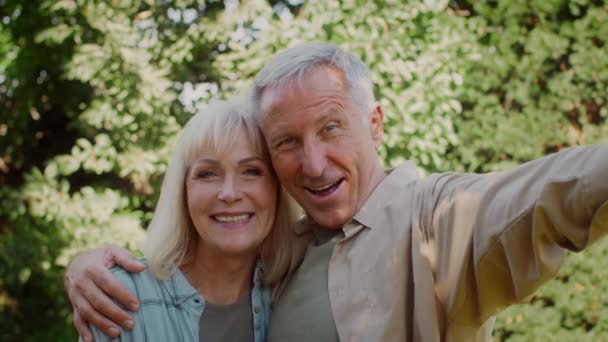 Feliz pareja de ancianos tomando selfie al aire libre, mirando a la cámara y sonriendo — Vídeos de Stock