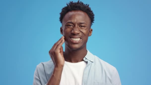 Zubní problémy. Mladý smutný africký Američan trpící bolestí zubů, masírující si zanícenou čelist — Stock video