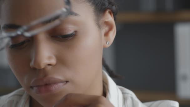 Jonge Afro-Amerikaanse vrouw manager die lijdt aan acute hoofdpijn, het nemen van een bril en masseren neus brug — Stockvideo