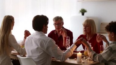 Şükran Günü 'nü kutlayan aile birlikte dua edip mutfakta el ele tutuşuyorlar.