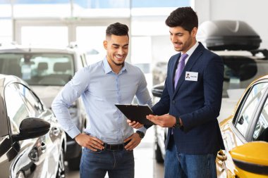 Müşteri araç özelliklerini gösteren çekici bir showroom yöneticisi