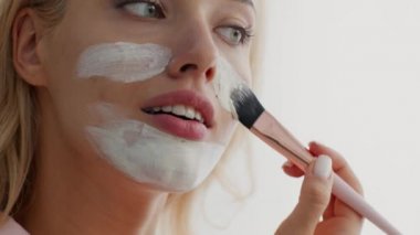 Cilt bakım konsepti. Genç Güzel Kadın Çamur Maskeyi Yüzüne Fırçayla Uyduruyor